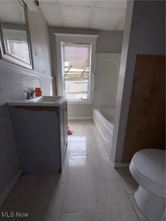 Bathroom with vanity, toilet, a paneled ceiling, and bathtub / shower combination