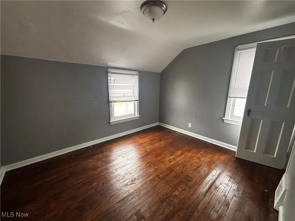 Bonus room with lofted ceiling, dark wood-style floors, and baseboards