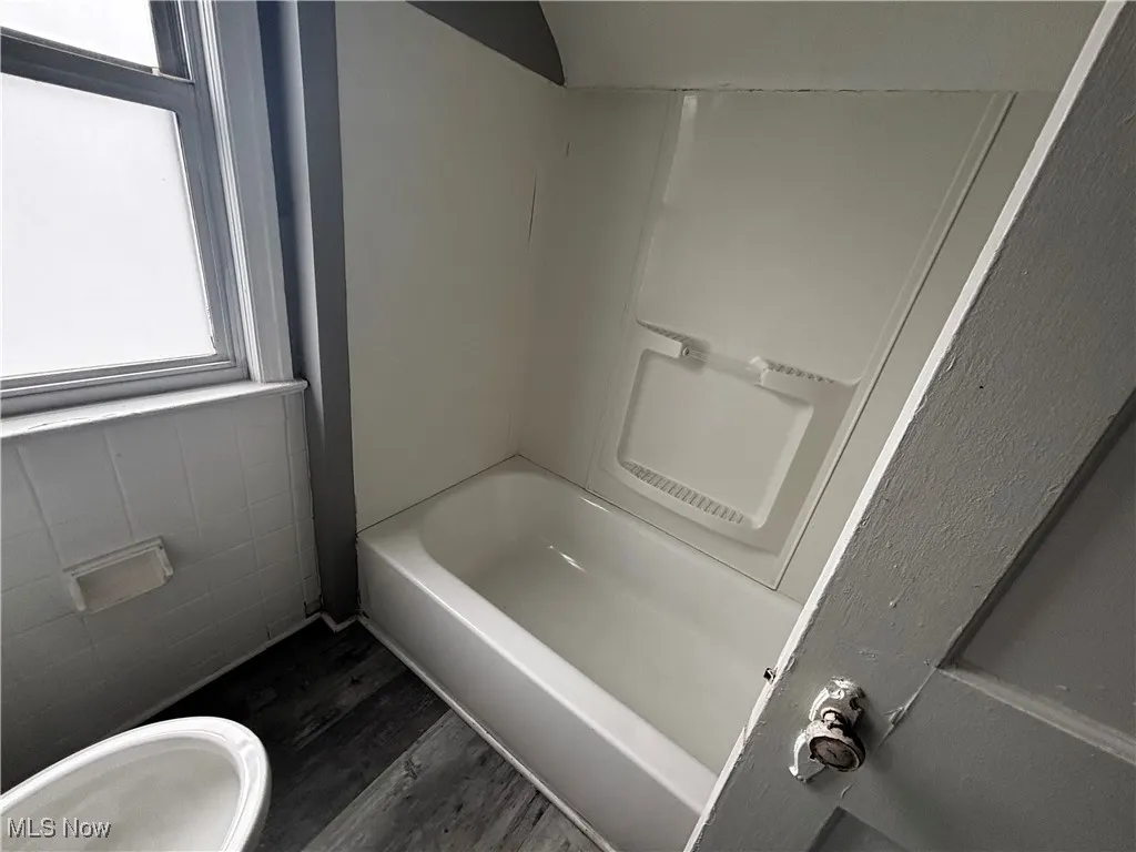 Bathroom featuring wood finished floors and shower / tub combination