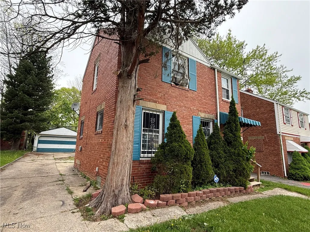 View of home's exterior with brick siding, an outdoor structure, and a detached garage