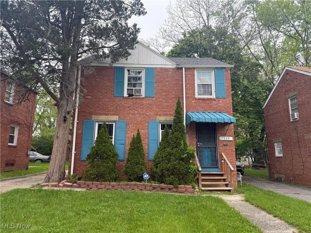 View of front of home featuring a front lawn, brick siding, and cooling unit