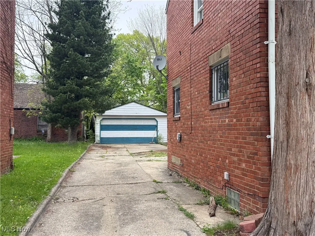 View of home's exterior with a garage, brick siding, an outbuilding, and a lawn
