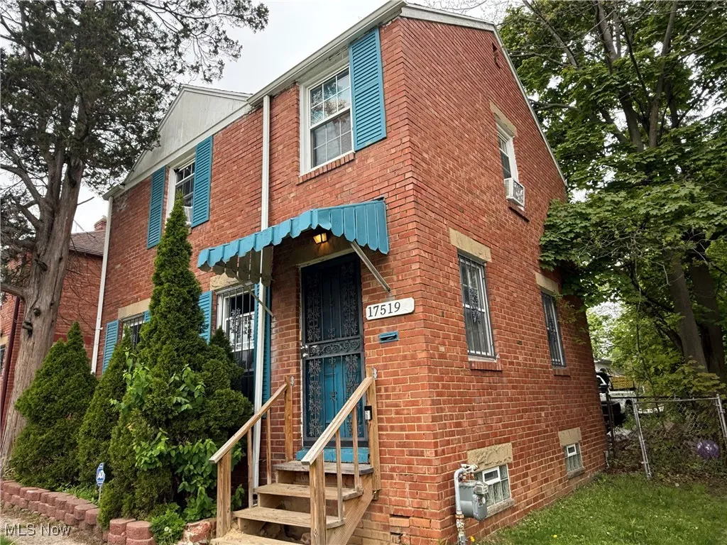 View of property featuring brick siding and fence