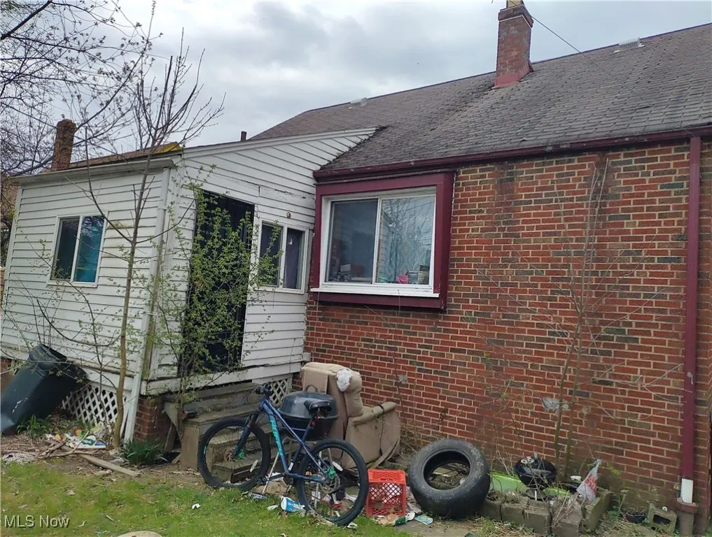 View of side of property featuring brick siding, a chimney, and roof with shingles