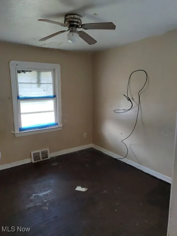 Spare room with ceiling fan and baseboards