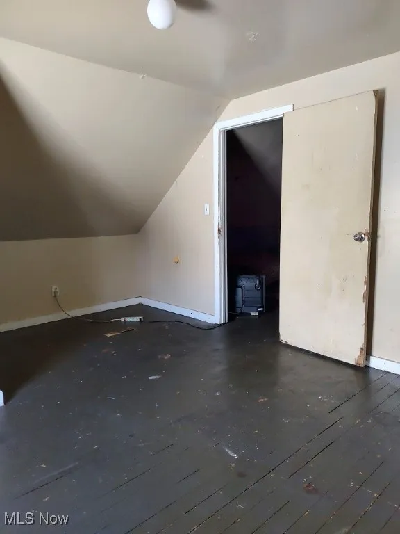 Bonus room with vaulted ceiling and baseboards