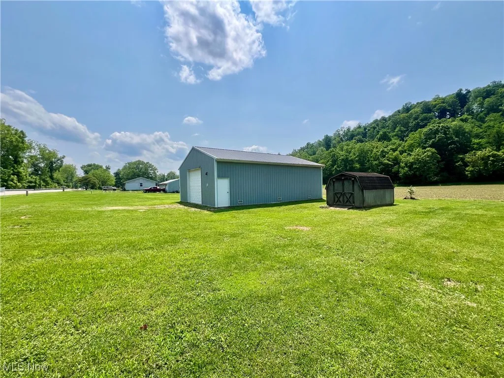 View of grassy yard with a garage and a storage unit