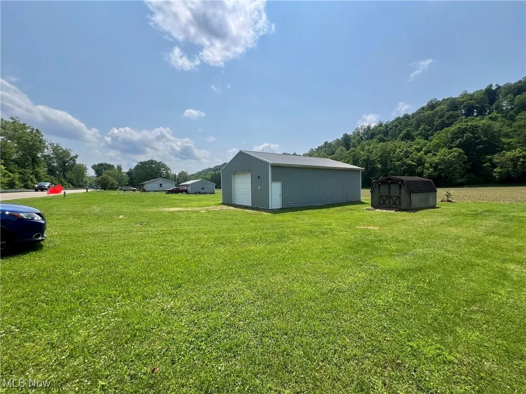 View of grassy yard with a detached garage and a storage shed