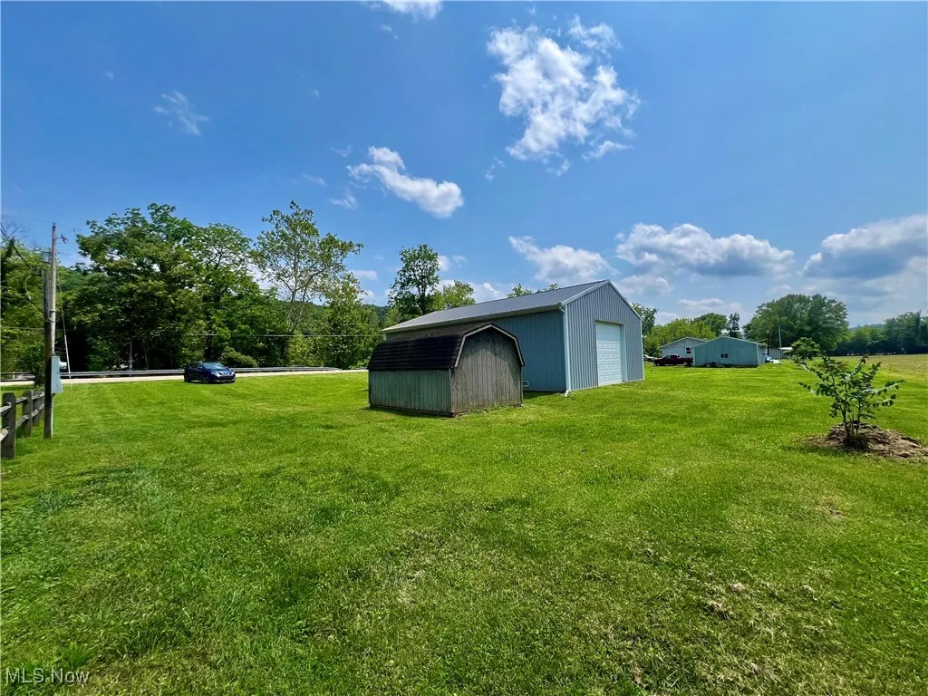View of green lawn featuring an outdoor structure and a detached garage