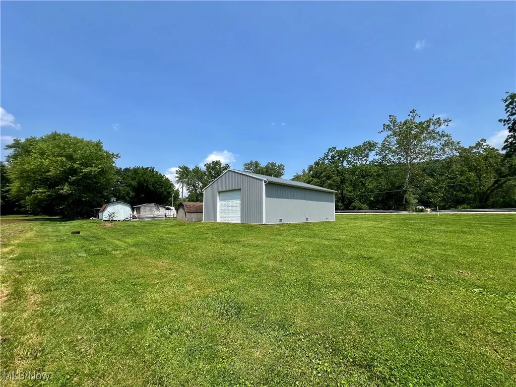 View of grassy yard featuring an outbuilding and a detached garage