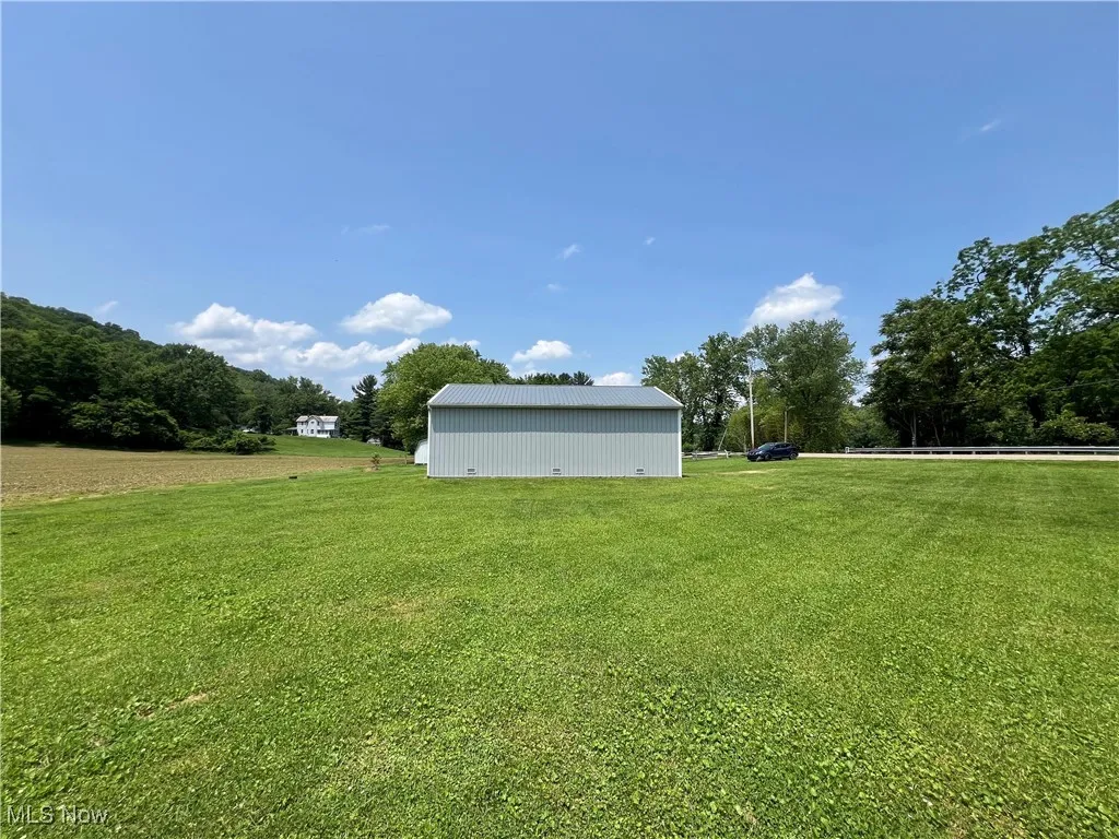 View of grassy yard featuring an outbuilding and an outdoor structure