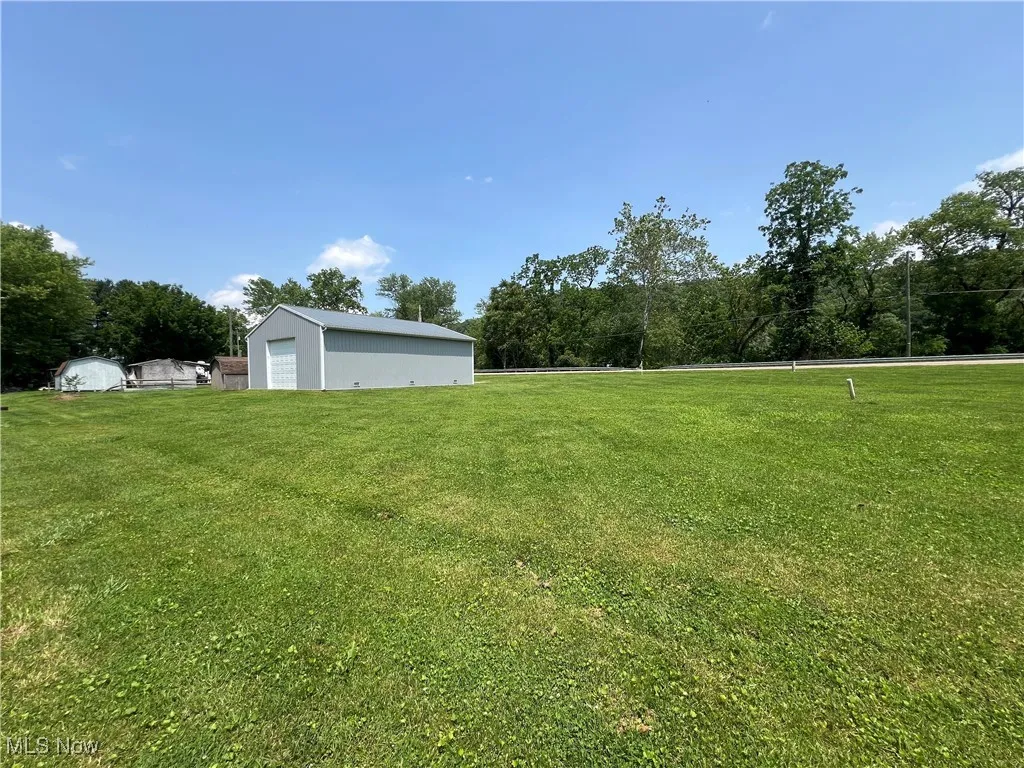 View of green lawn featuring a detached garage and an outbuilding