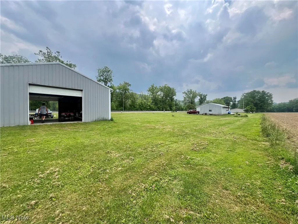 View of grassy yard with a detached garage, an outbuilding, and an outdoor structure
