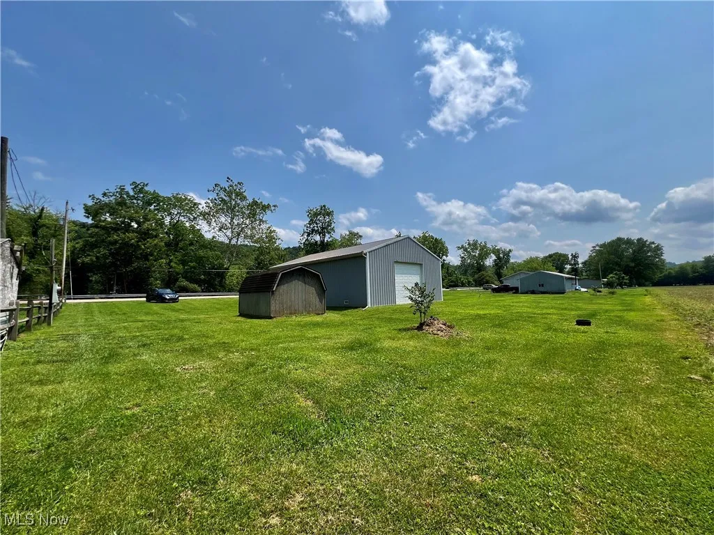 View of grassy yard featuring a detached garage and a storage shed