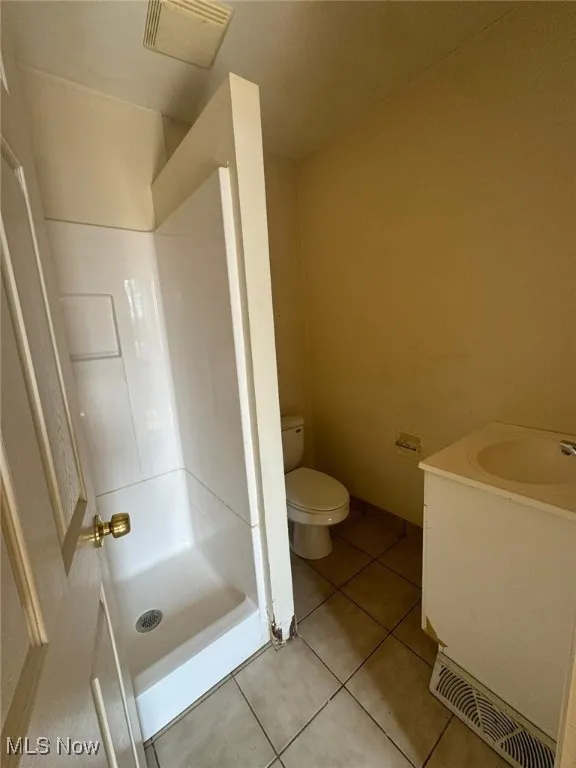Bathroom with toilet, tile patterned flooring, a stall shower, and vanity