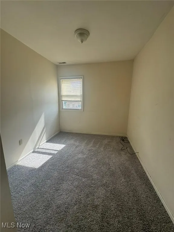 Empty room featuring carpet flooring and baseboards