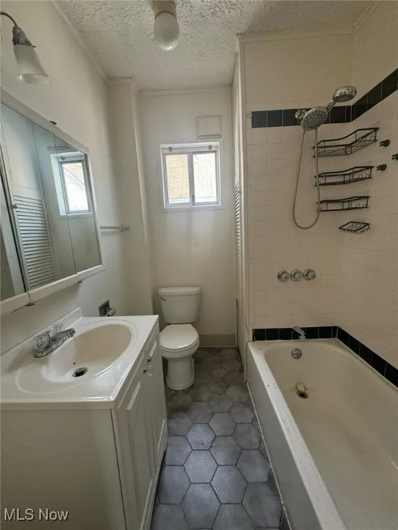 Full bath featuring plenty of natural light, vanity, toilet, tile patterned flooring, and a textured ceiling