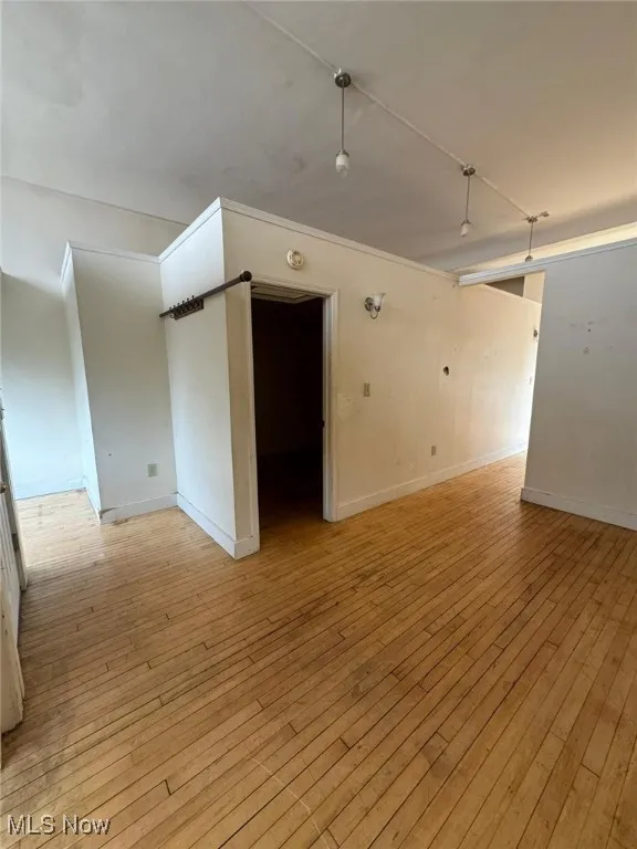 Unfurnished room featuring light wood-style floors, baseboards, and a smoke detector