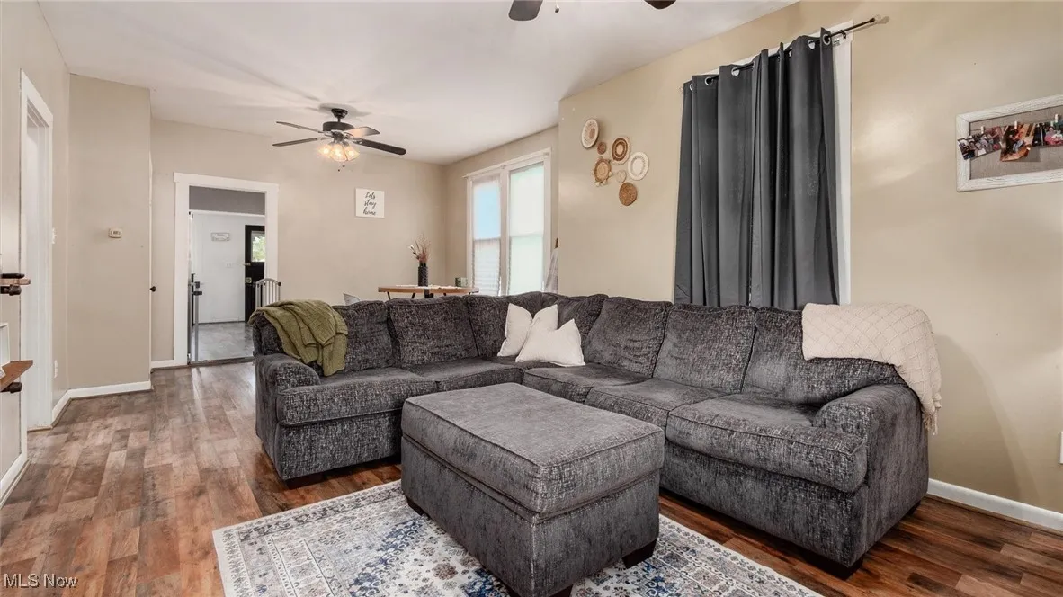 Living room with a ceiling fan, wood finished floors, and baseboards