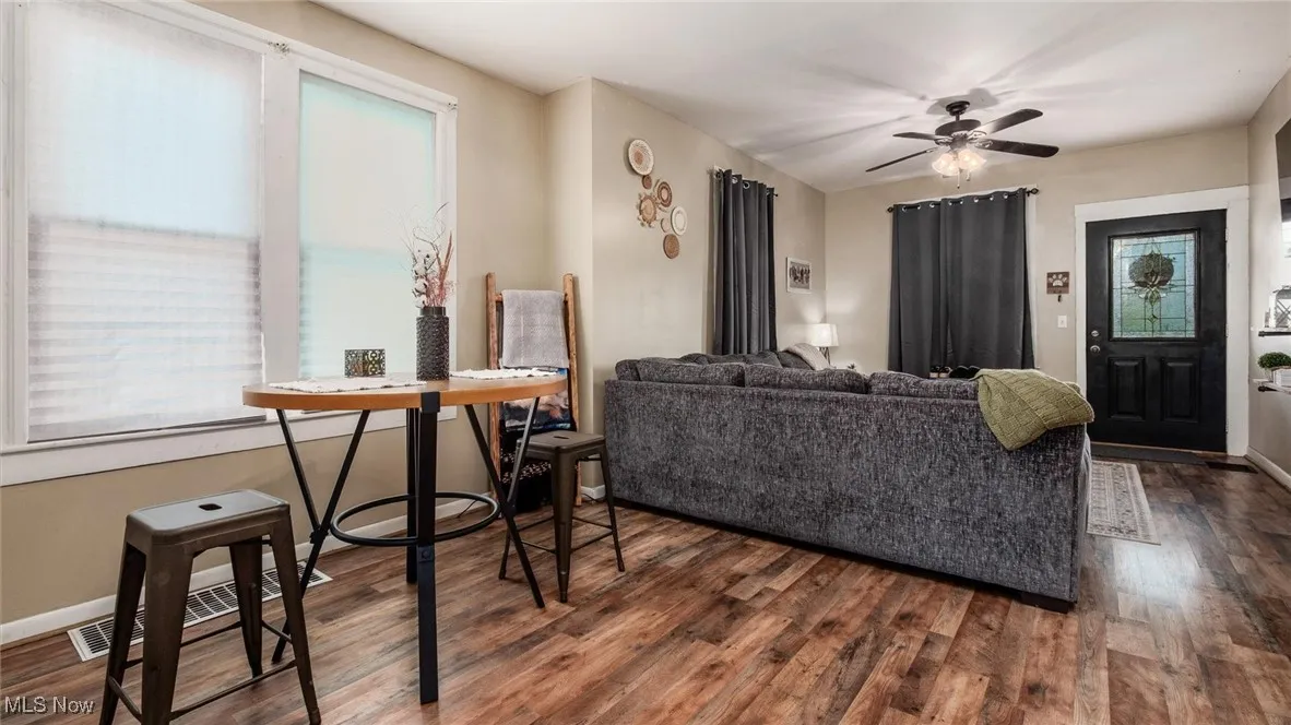 Living room featuring plenty of natural light, dark wood finished floors, and ceiling fan