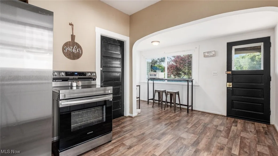 Kitchen featuring stainless steel appliances, arched walkways, and wood finished floors