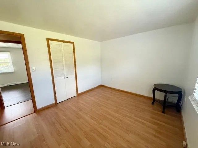 Unfurnished bedroom with light wood-style floors and a closet