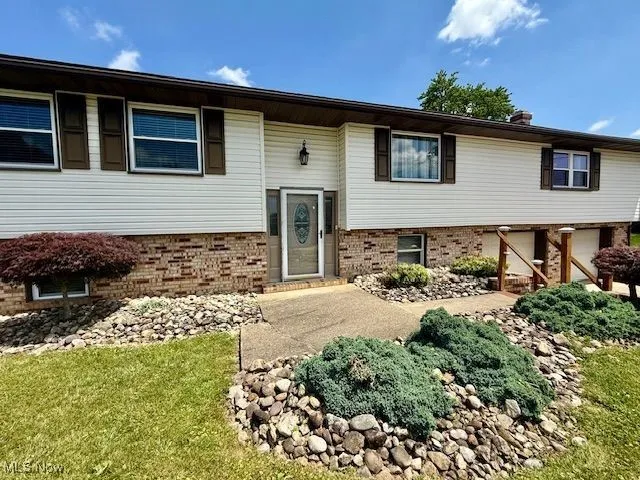 Bi-level home featuring brick siding and a front lawn