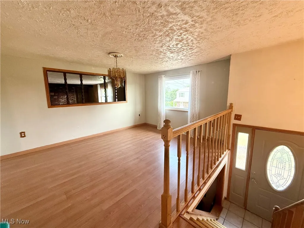 Foyer featuring wood finished floors, a textured ceiling, a chandelier, and baseboards