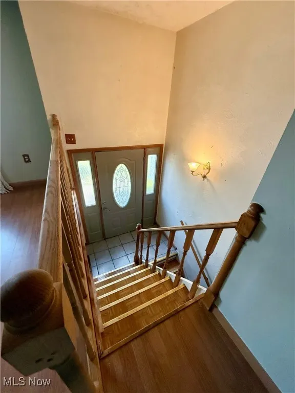 Foyer featuring stairs, wood finished floors, baseboards, and a high ceiling
