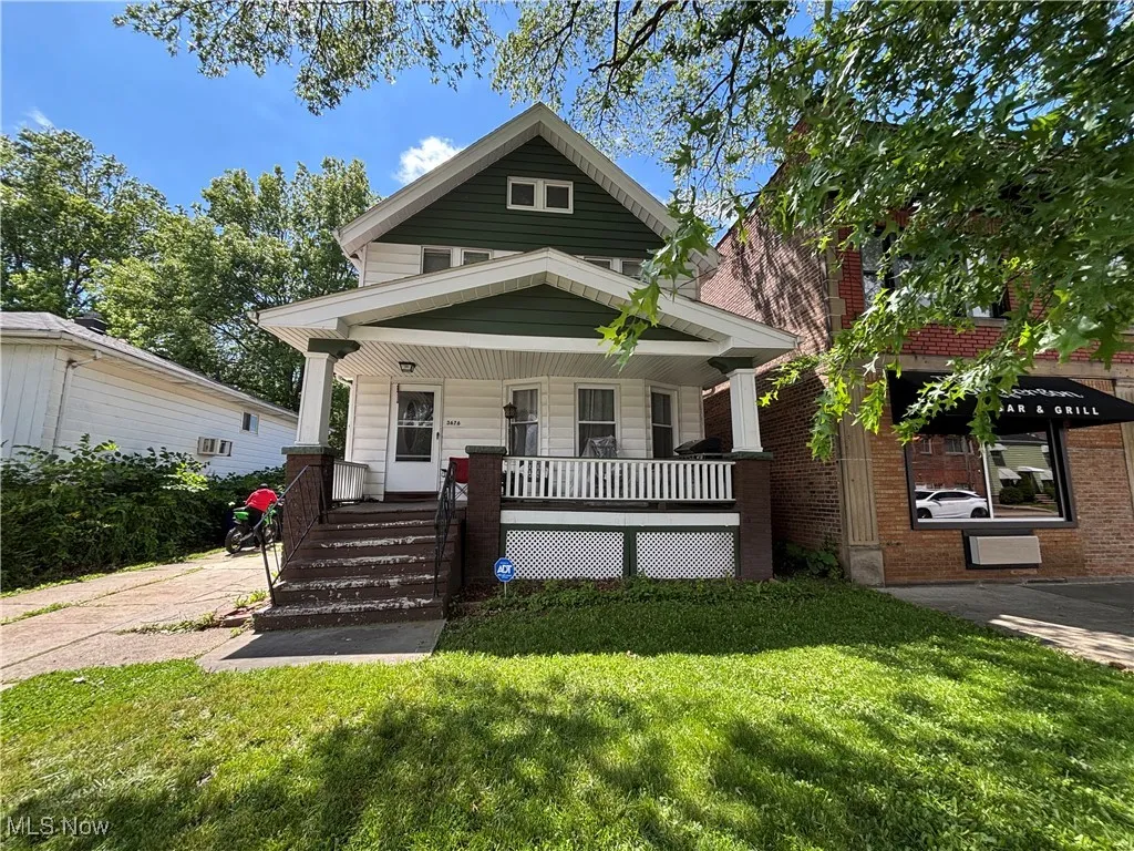 View of front facade featuring a porch, a front yard, and brick siding