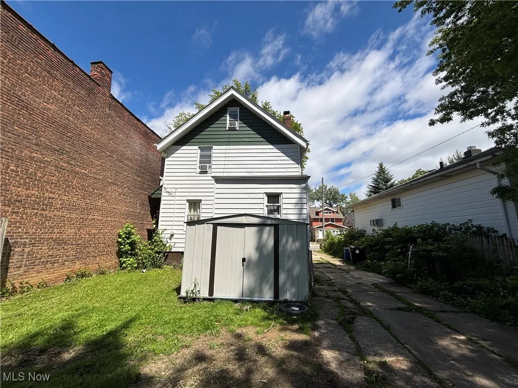 Rear view of house featuring a chimney and a lawn