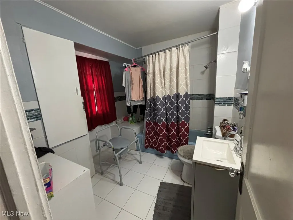 Full bath with vanity, shower / bath combo with shower curtain, toilet, and tile patterned flooring