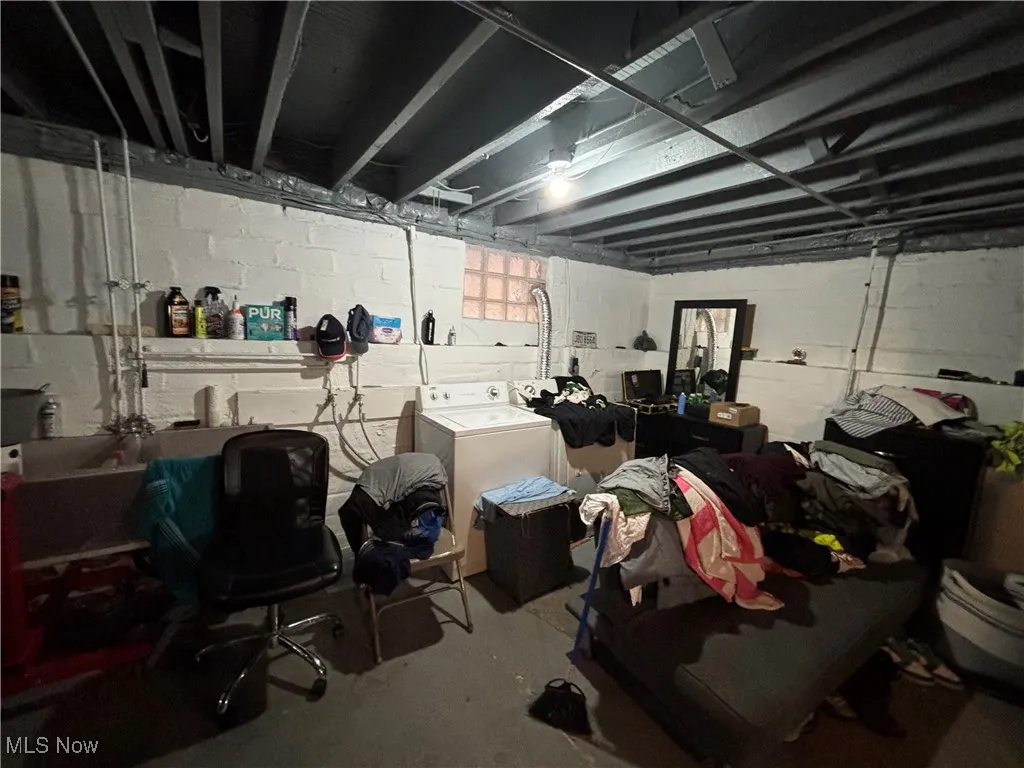 Unfinished basement with washer and clothes dryer and concrete block wall