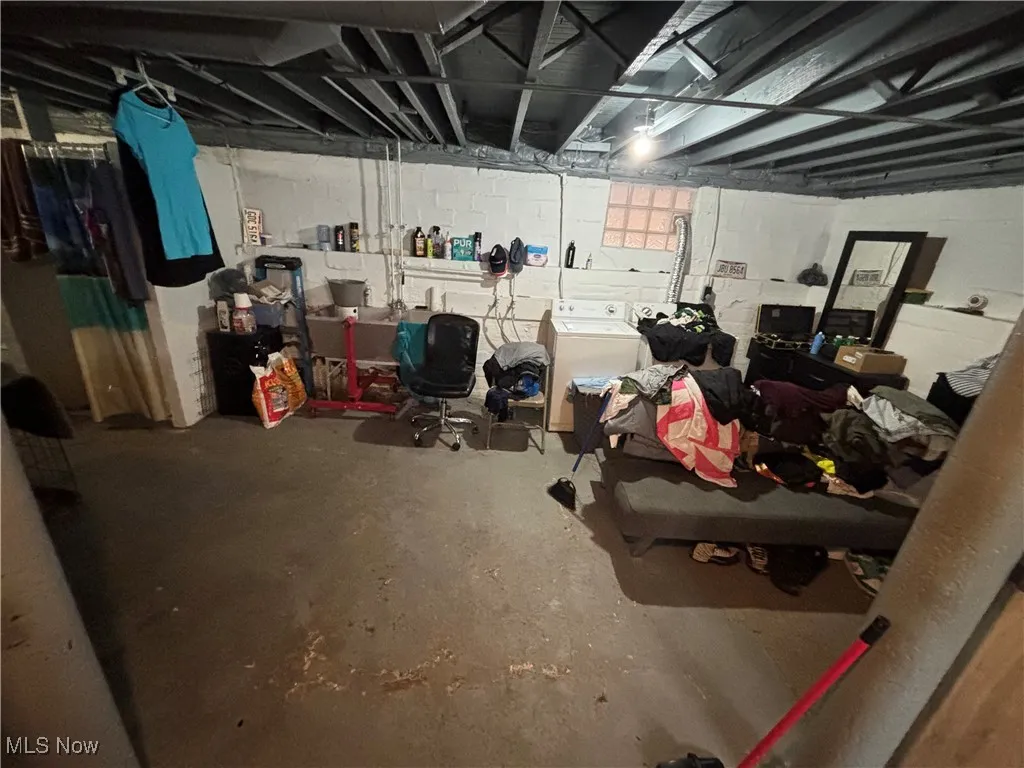 Unfinished below grade area featuring washer / clothes dryer and concrete block wall