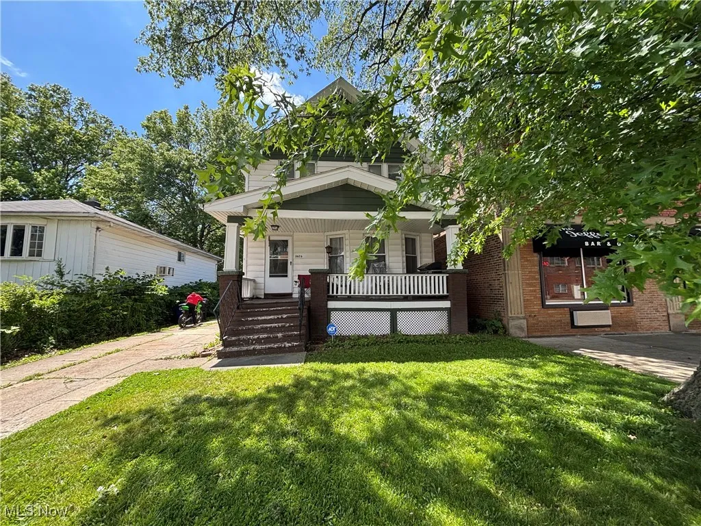 View of front facade with covered porch, a front yard, and brick siding