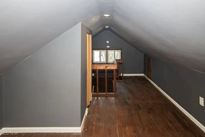Bonus room with vaulted ceiling, hardwood / wood-style flooring, and baseboards