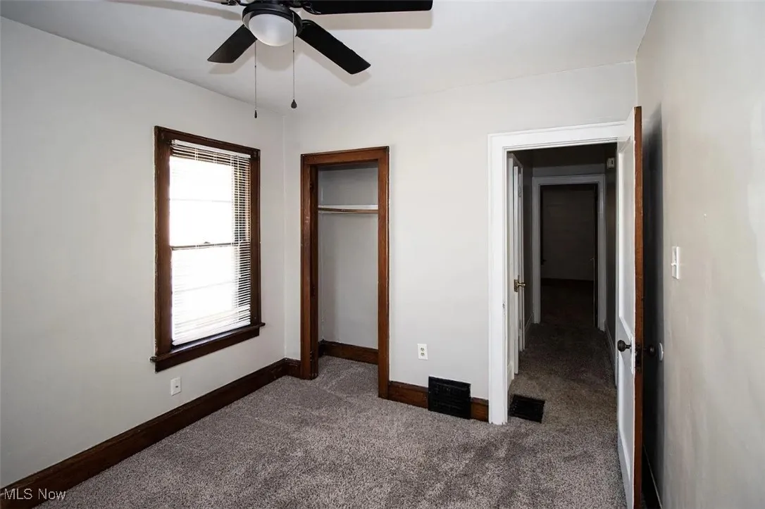 Unfurnished bedroom with carpet, baseboards, a closet, and a ceiling fan