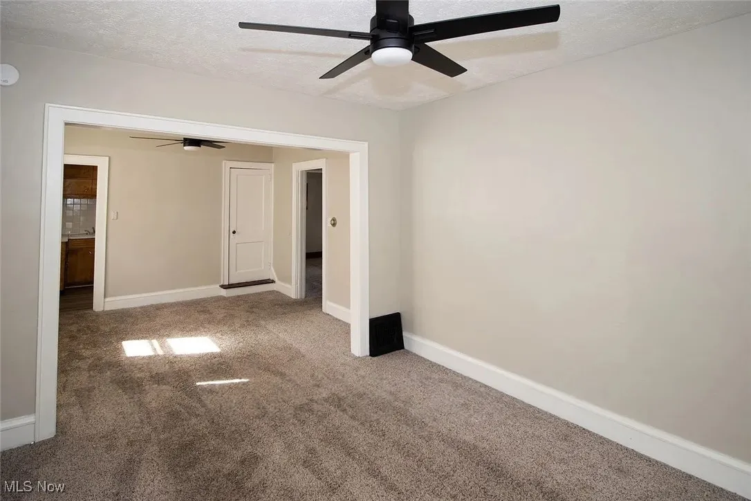 Carpeted spare room with a ceiling fan, a textured ceiling, and baseboards