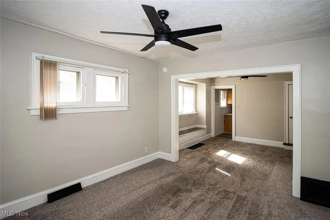 Unfurnished room with ceiling fan, a textured ceiling, carpet floors, and baseboards