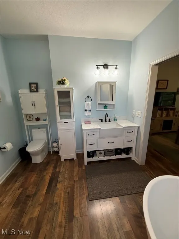 Full bathroom featuring vanity, toilet, hardwood / wood-style flooring, and a freestanding tub