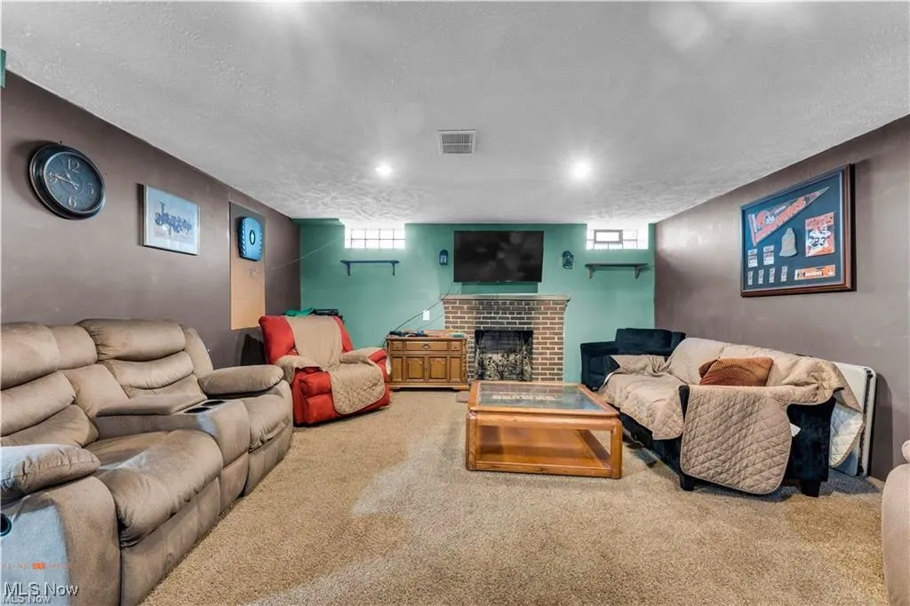 Living area with carpet, a fireplace, plenty of natural light, and a textured ceiling
