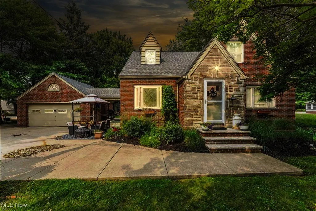 English style home with stone siding, concrete driveway, an attached garage, and brick siding