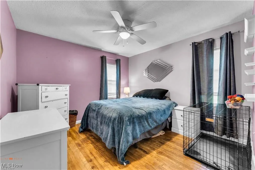 Bedroom with light wood-type flooring, a textured ceiling, ceiling fan, and baseboards