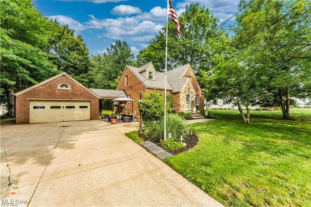 View of front of house with a front lawn, driveway, brick siding, and an attached garage