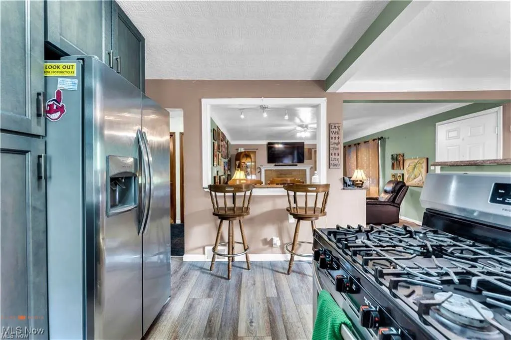 Kitchen featuring appliances with stainless steel finishes, light wood-type flooring, baseboards, a ceiling fan, and a textured ceiling