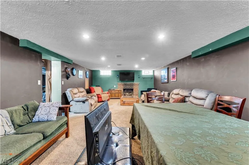 Living room with light colored carpet, a fireplace, recessed lighting, and a textured ceiling