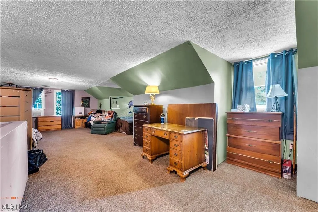 Bedroom featuring a textured ceiling, carpet floors, multiple windows, and lofted ceiling