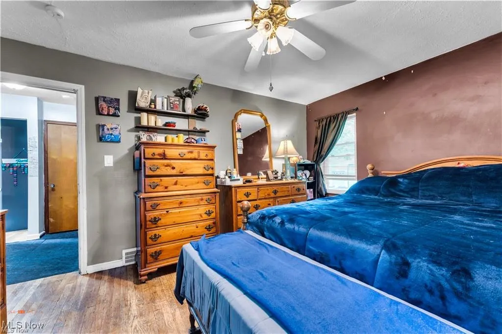 Bedroom featuring wood finished floors, baseboards, a textured ceiling, and a ceiling fan