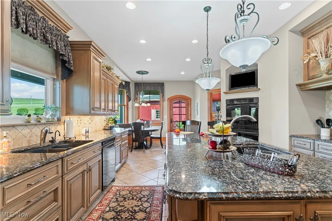 Kitchen with backsplash, black dishwasher, recessed lighting, a chandelier, and a sink