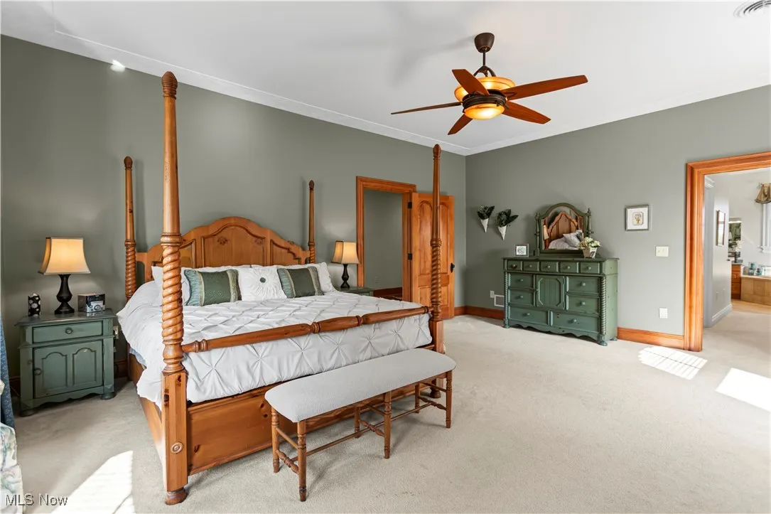 Bedroom featuring light colored carpet, baseboards, crown molding, and ceiling fan